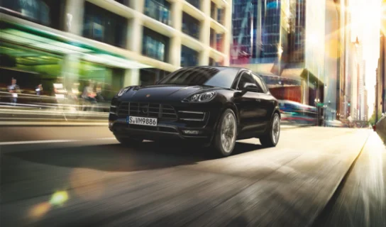 Ein schwarzer Porsche fährt schnell auf einer asphaltierten Straße.