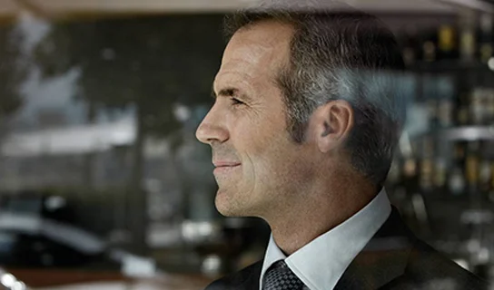 Mann im Anzug schaut aus einem Fenster raus.