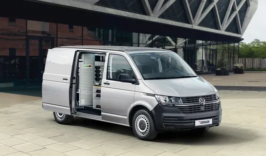Der VW T6.1 Transporter Kasten in silber steht vor einem Gebäude mit Glasfassade.